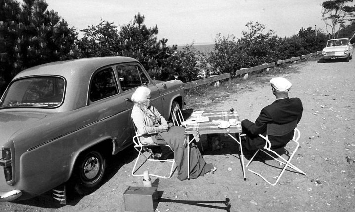 Et ældre ægtepar drikker kaffe foran deres Volvo Amazon. Tiden kunne godt føles lang, når man havde forladt arbejdsmarkedet, men var det kommunernes opgave at gøre noget ved det?
